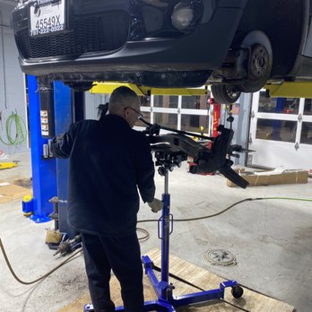 A mechanic using a transmission jack under a car